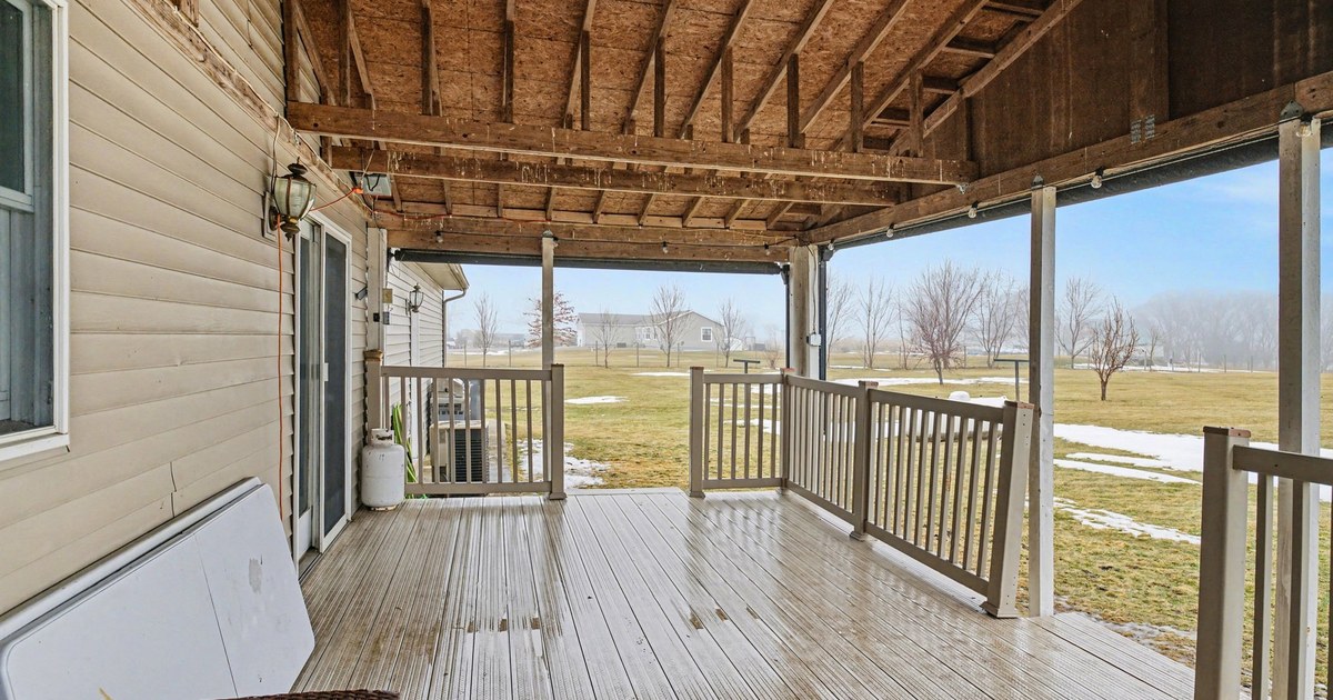 A covered front porch framing a view of open countryside.