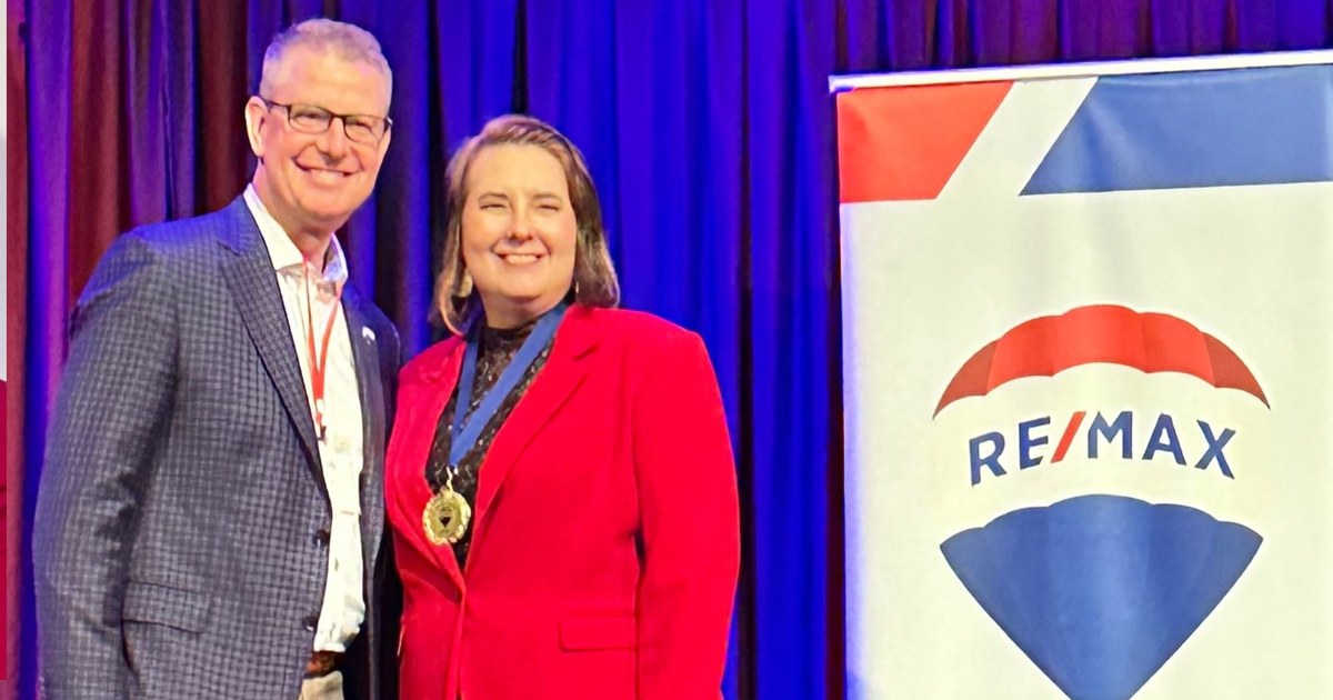 Lisa Collio accepting a RE/MAX Results award on stage.