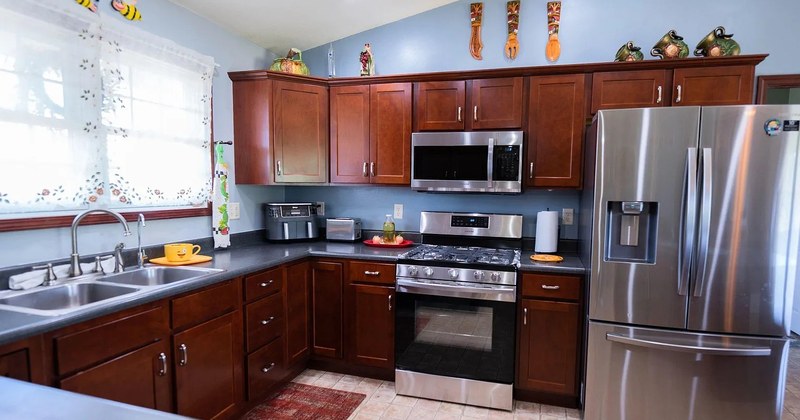 A warm kitchen with cherry cabinets, stainless-steel appliances, and tile floors.