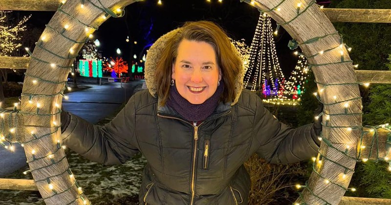 Lisa Collio smiling, framed by an arch of holiday lights.