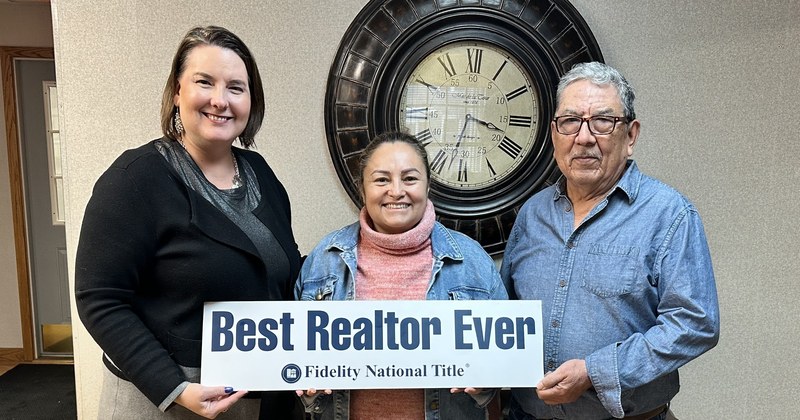 Lisa Collio with two clients holding a "Best Realtor Ever" sign after closing.