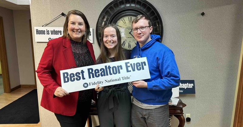 Lisa Collio with two clients holding a "Best Realtor Ever" sign after closing.
