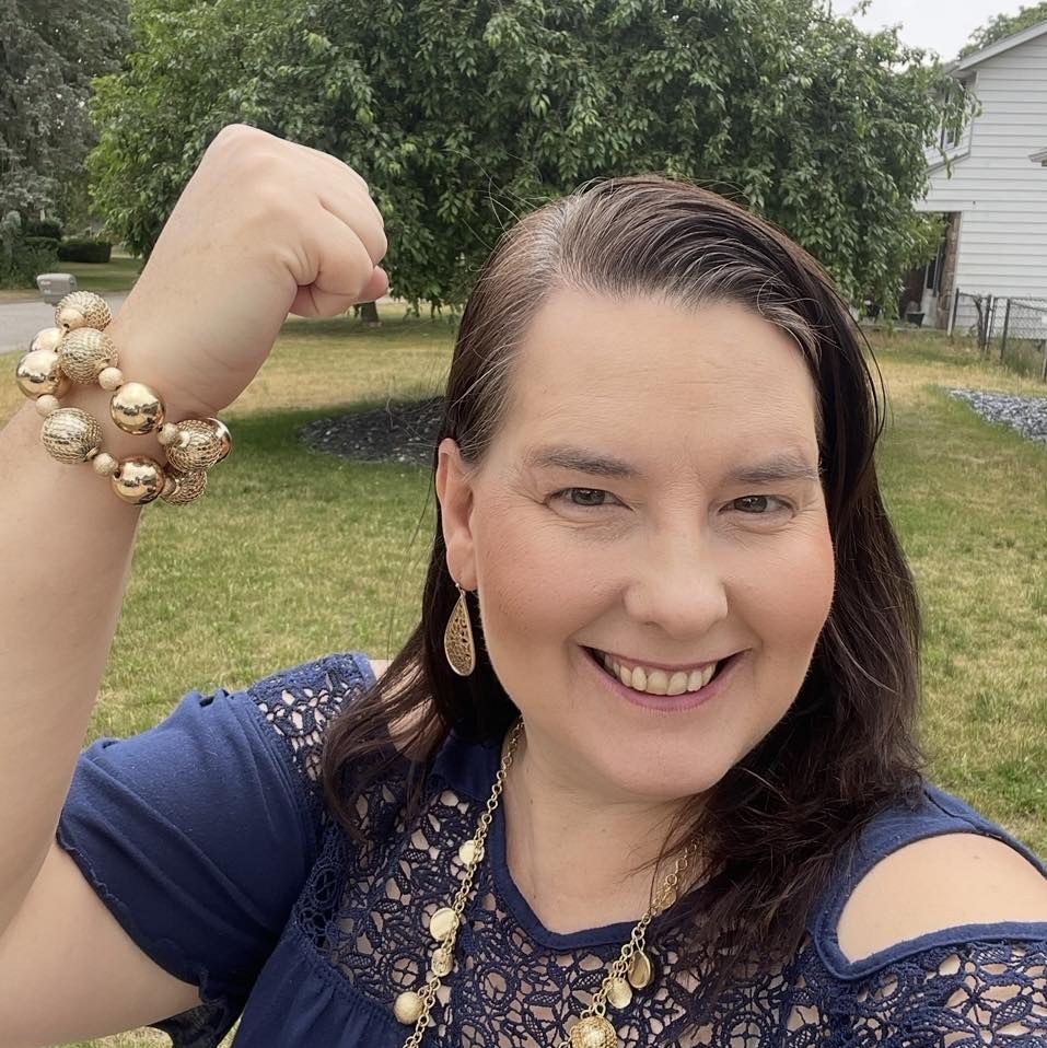 Lisa Collio smiling outdoors, raising her arm in a cheerful gesture.