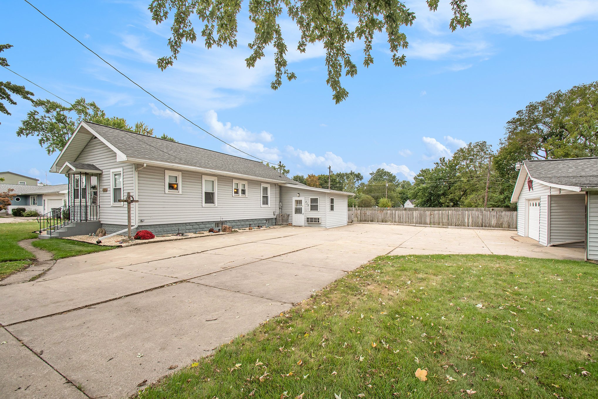 A single-story ranch home with a long driveway and a fenced yard.