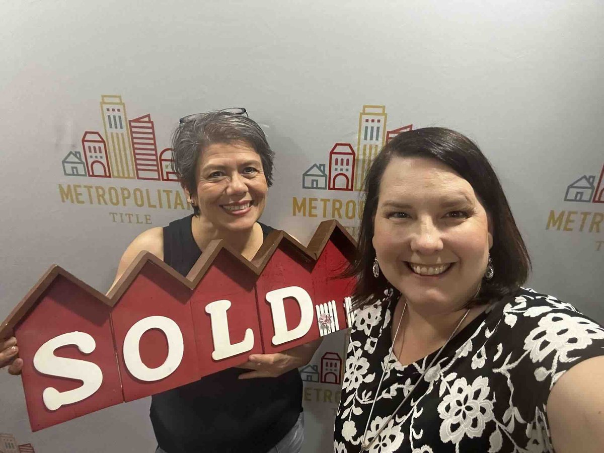 Lisa Collio with a title company representative holding a SOLD sign.