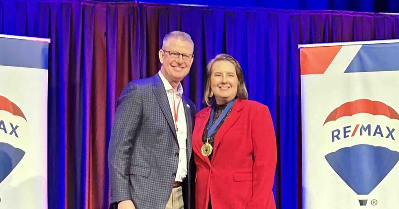 Lisa Collio receiving recognition on stage at a RE/MAX Results awards event.