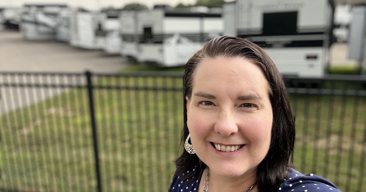 Lisa Collio outdoors beside a fenced lot lined with recreational vehicles.