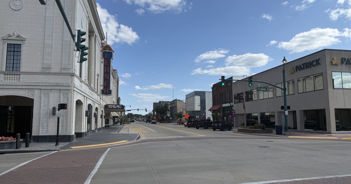 A downtown Elkhart intersection on a clear day, with the Lerner Theatre's vertical marquee on the left and brick commercial buildings along the right.
