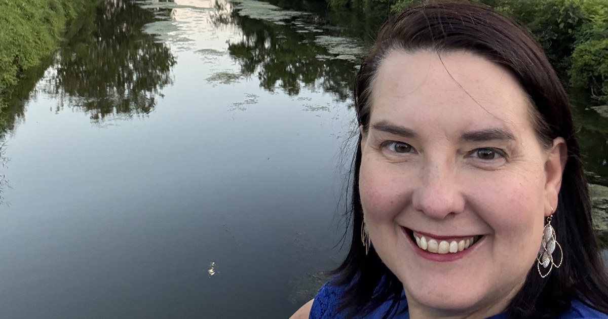 Lisa Collio smiling beside the millrace on a summer evening.