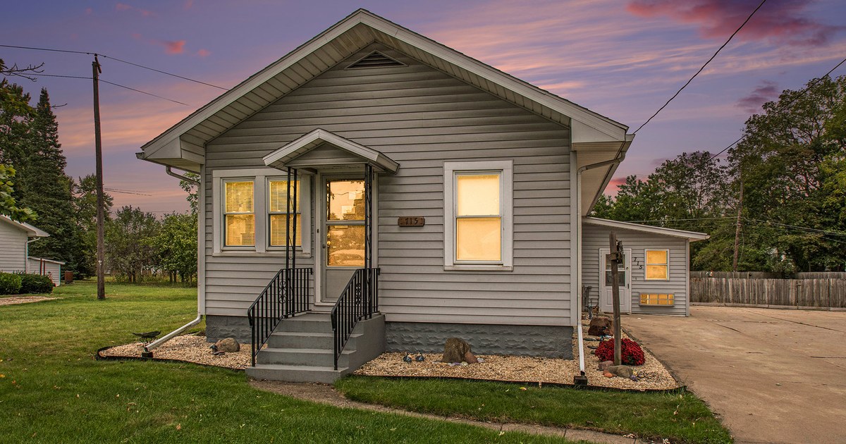 A small single-story Goshen home with a lit porch at dusk.