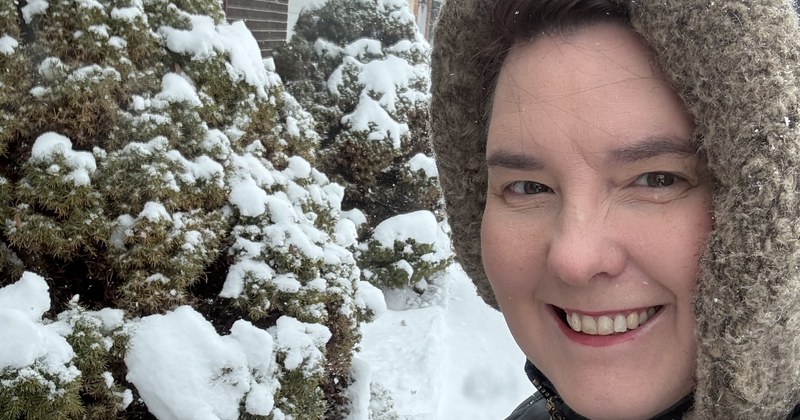 Lisa Collio outdoors in winter beside snow-covered shrubs.