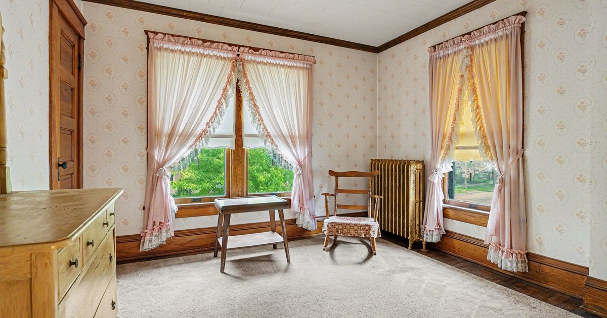 An empty room in an older Goshen home with tall windows and wood trim.